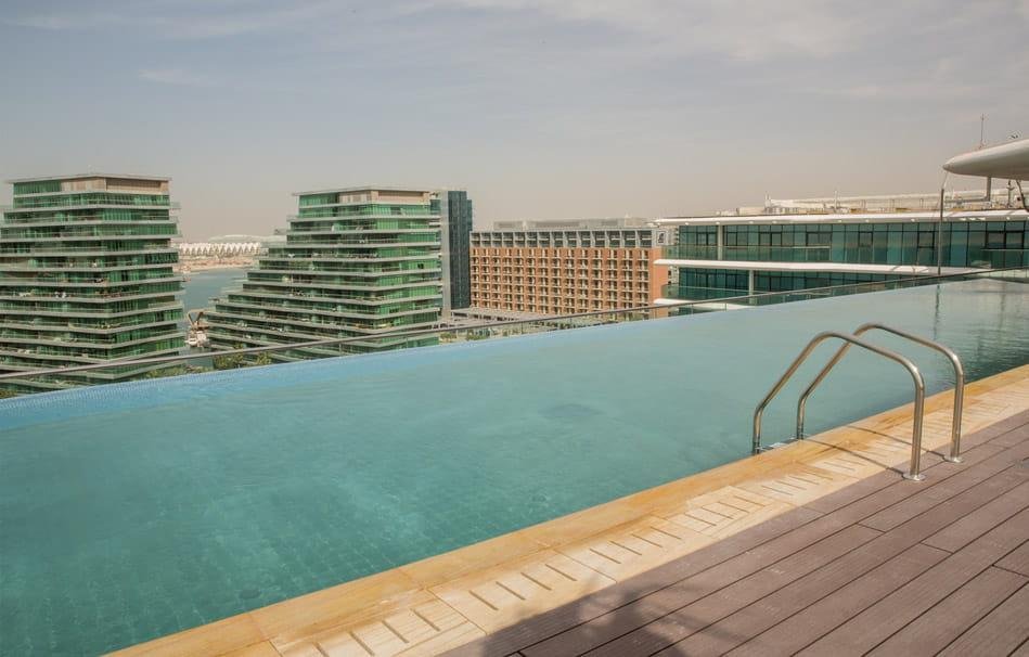 Infinity pool and outdoor amenity deck at Al Hadeel, Al Raha Beach